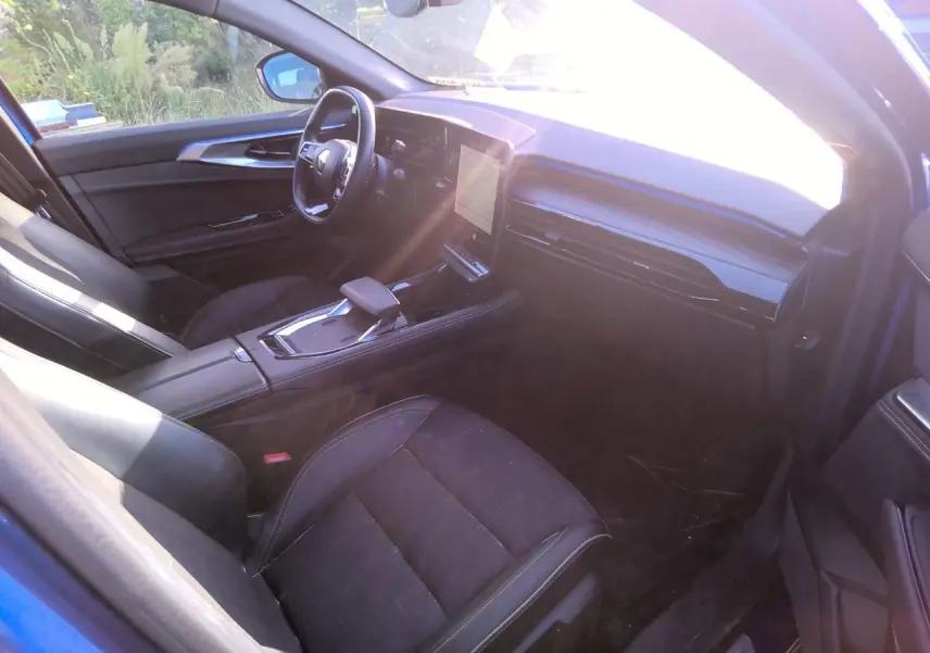 Intérieur côté conducteur du Renault Austral 2024 bleu métal, avec tableau de bord numérique et sellerie mixte noire.