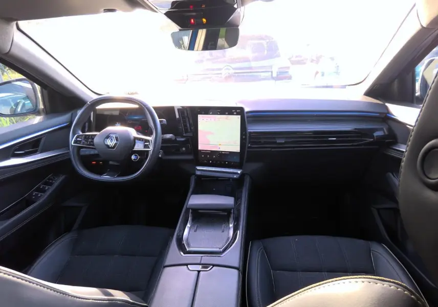 Intérieur du Renault Austral 2024 vu de l'arrière, tableau de bord moderne avec écran tactile vertical et volant compact noir.