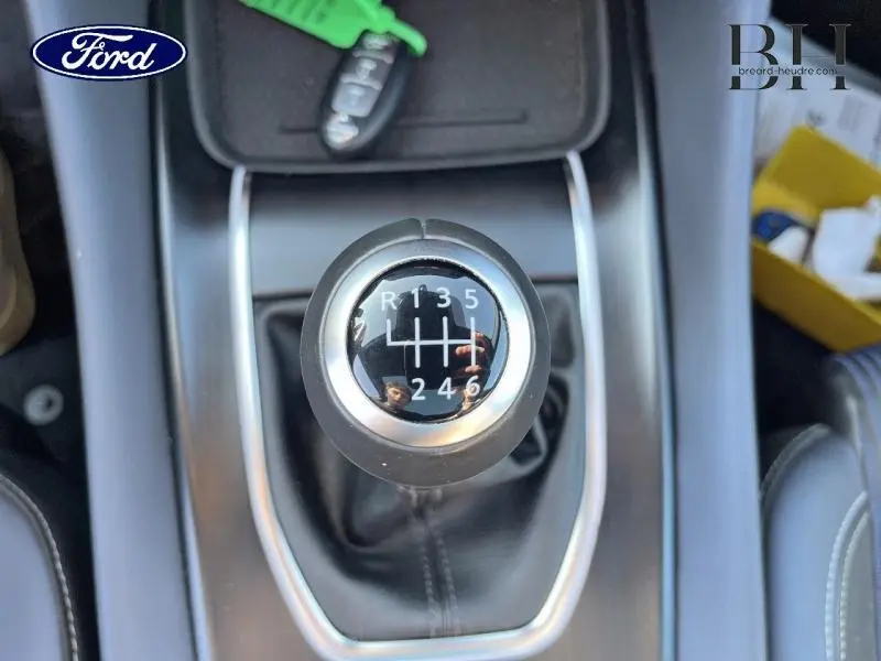 Gros plan sur le pommeau de levier de vitesse manuel du Nissan Qashqai gris Argile, avec marquages des vitesses visibles.