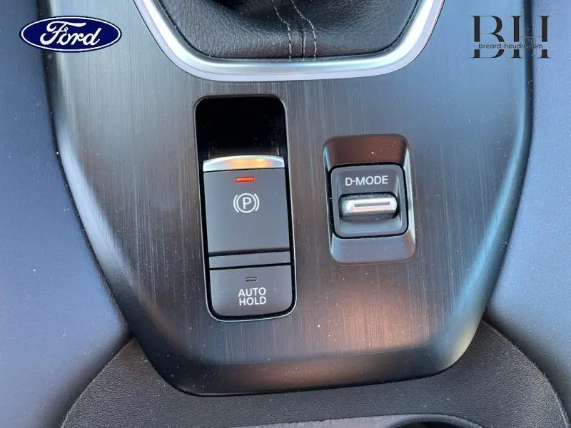 Gros plan sur la console centrale noire avec commandes de frein à main électrique et mode de conduite D-MODE.