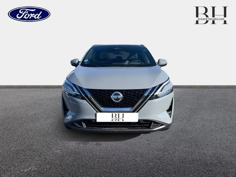 Vue de face d'un Nissan Qashqai 1.3 Mild Hybrid gris Argile avec calandre noire et phares LED fins.