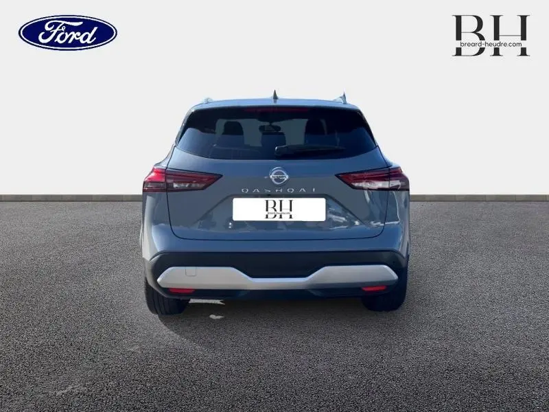 Vue arrière d'un Nissan Qashqai 1.3 Mild Hybrid gris Argile avec feux arrière LED et lunette arrière surteintée.