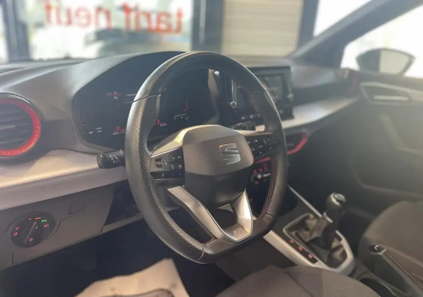 Vue intérieure centrée sur le volant sport cuir noir avec logo SEAT et levier de vitesse manuel du SEAT Arona 2024.