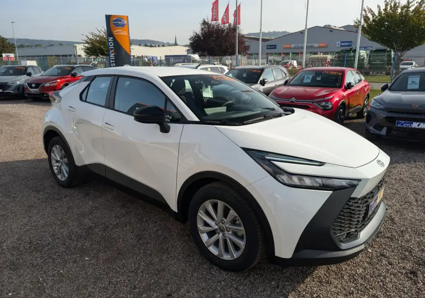 Toyota C-HR blanc en 3/4 avant droit, avec calandre noire et jantes alliage 17 pouces visibles.