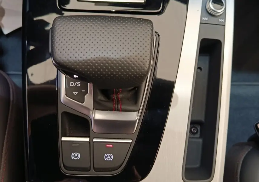 Gros plan sur la console centrale de l'Audi Q5 2023 hybride rechargeable, montrant le levier de vitesses automatique en cuir perforé.