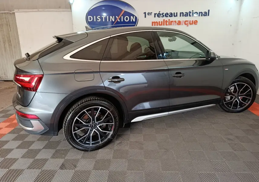 Vue latérale droite d'un Audi Q5 gris clair hybride rechargeable 2023 avec jantes noires et détails chromés.
