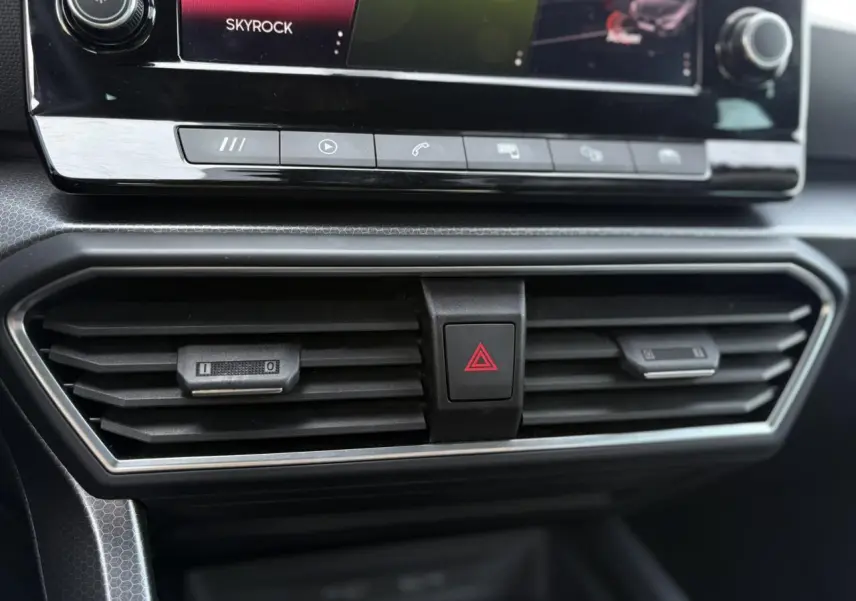 Détail des aérateurs centraux et bouton de warning sur le tableau de bord du SEAT LEON 2024 gris Magnétique.