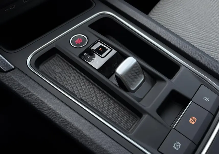 Gros plan sur la console centrale noire de la SEAT LEON 2.0 TDI 150 DSG Style avec levier de vitesse électronique et bouton Start/Stop rouge.
