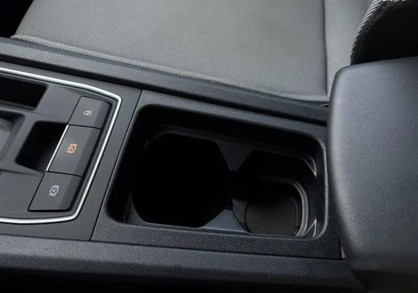 Gros plan sur la console centrale noire avec accoudoir et commandes du frein à main électrique dans SEAT Leon gris.