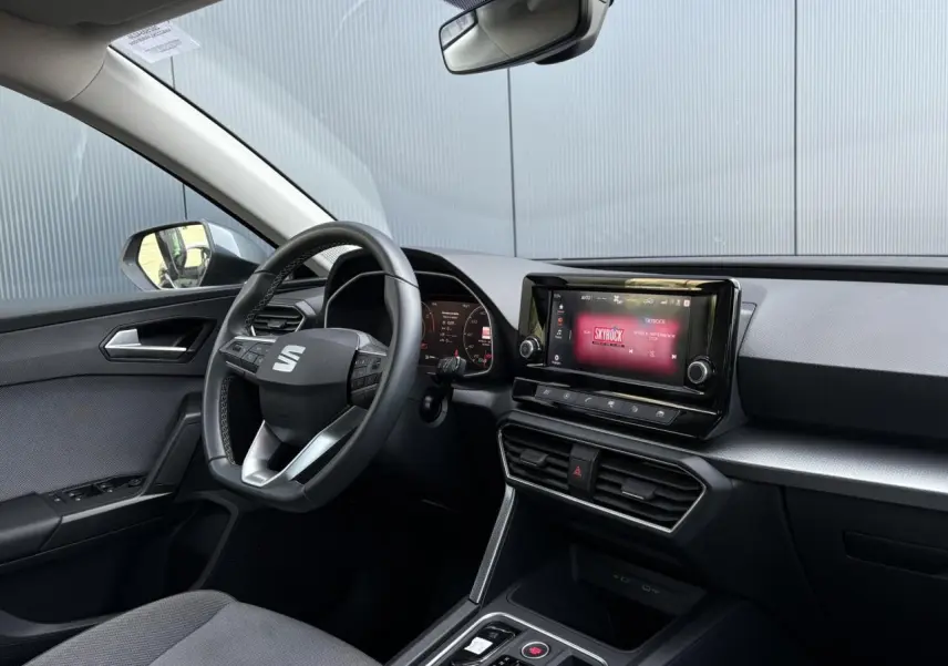 Intérieur du SEAT Leon 2024 vu côté conducteur, volant cuir multifonctions et écran tactile affichant Skyrock.