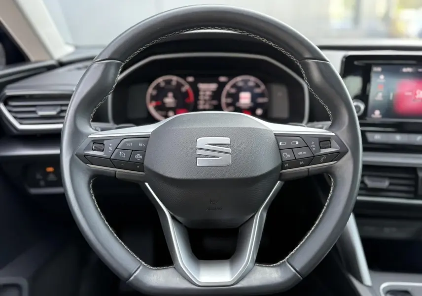 Volant cuir multifonction de la SEAT LEON 2024 avec commandes intégrées, tableau de bord digital et écran tactile visible.