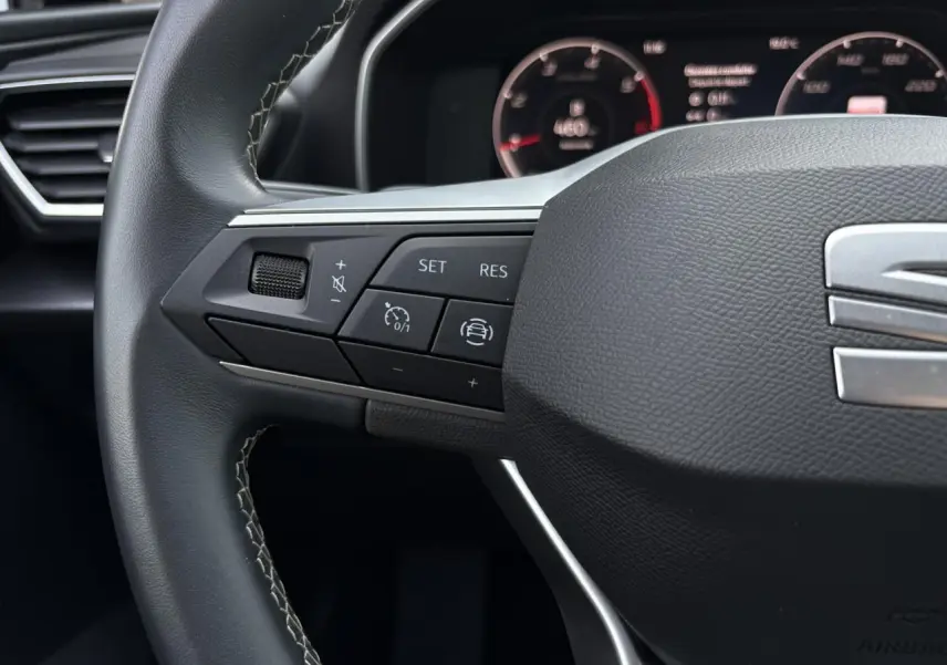 Gros plan sur le volant cuir multifonction de la SEAT LEON 2024 avec commandes de régulateur et assistance au pilotage.