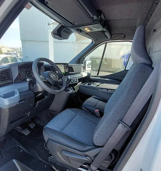 Vue intérieure côté conducteur du Nissan Interstar Fourgon blanc 2025, avec siège gris et tableau de bord moderne.