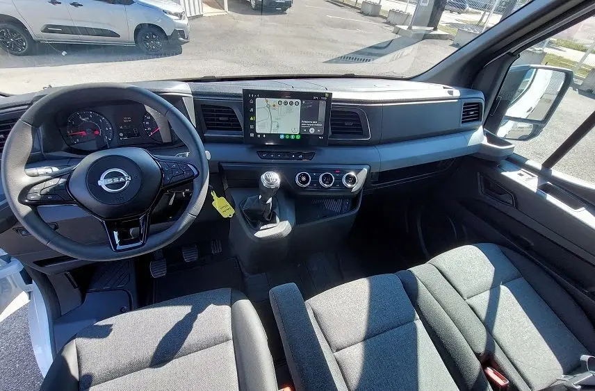 Vue intérieure avant du Nissan Interstar Fourgon blanc 2025, tableau de bord moderne avec écran tactile et volant multifonction.
