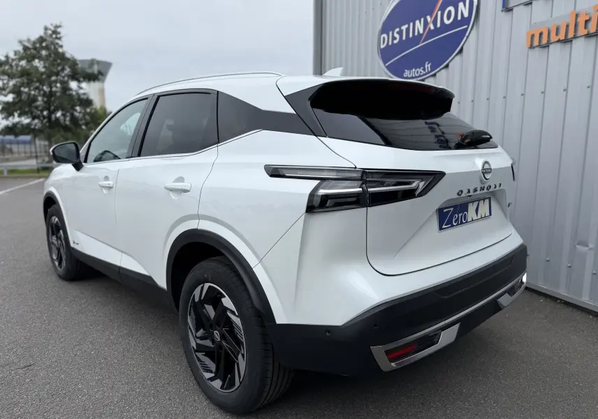 Vue 3/4 arrière droite du Nissan Qashqai blanc nacré avec feux arrière LED et jantes noires brillantes.