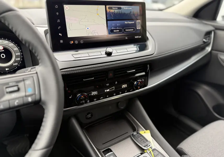 Vue intérieure côté conducteur du Nissan Qashqai 2025, mettant en valeur l'écran tactile et la console centrale moderne.
