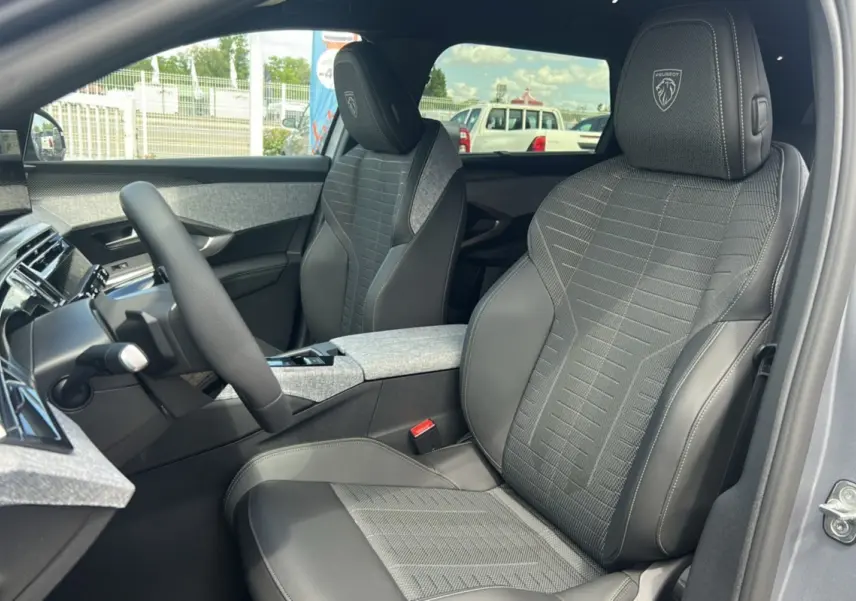 Vue intérieure du PEUGEOT 5008 HYBRID 145 GT 7 places, sièges avant gris avec logo Peugeot brodé sur les appuie-têtes.