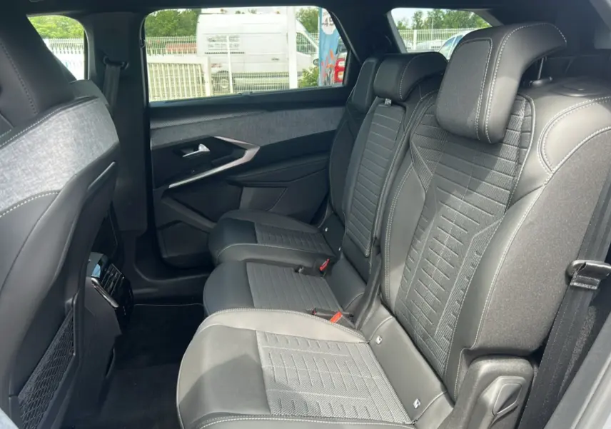 Vue latérale droite de l'habitacle arrière du Peugeot 5008 Hybrid 145 GT 7 places avec sièges en cuir gris et tissu.