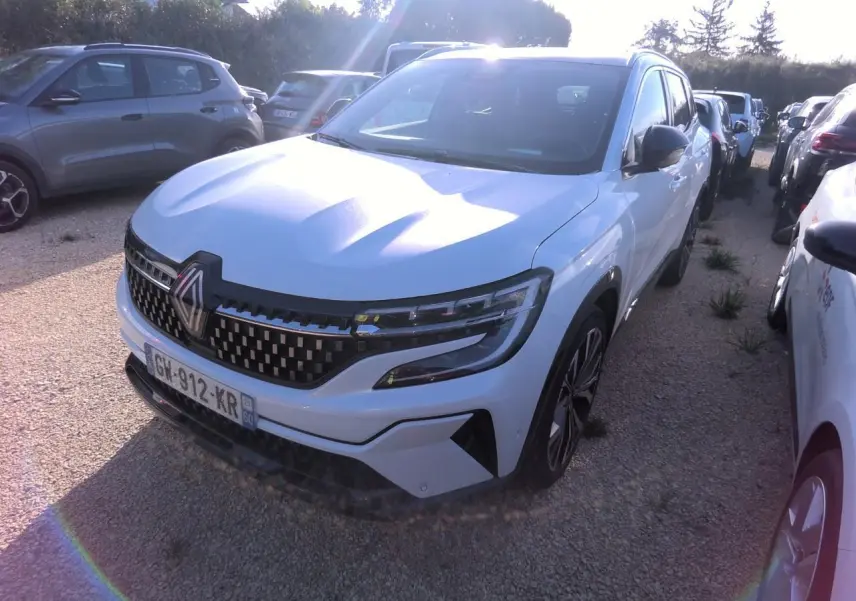 Renault Austral blanc nacré vu de face droite, calandre damier ice black et jantes alliage 20 pouces visibles.