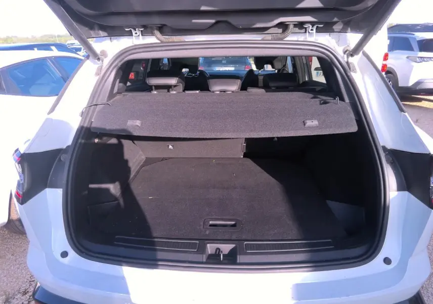 Coffre ouvert vu de l'arrière d'un Renault Austral blanc nacré, montrant l'espace de chargement vide et la plage arrière.