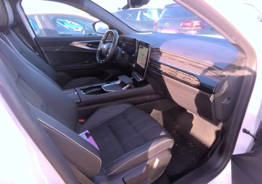 Intérieur côté conducteur du Renault Austral blanc nacré 2024, avec tableau de bord moderne et écran tactile vertical.