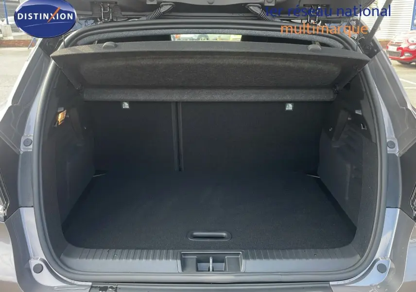 Coffre ouvert d'un Renault Captur E-Tech hybride gris Cassiopée métal avec toit noir, montrant un espace de chargement vide.