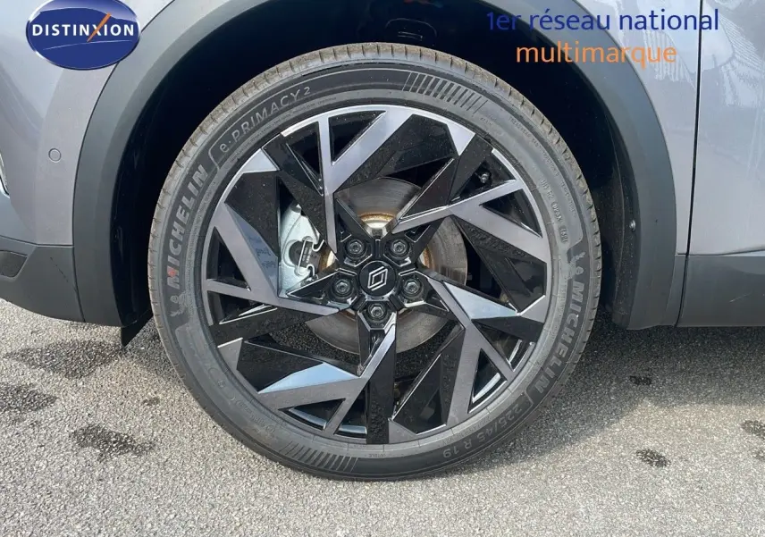 Gros plan sur la roue avant gauche du Renault Captur E-Tech gris Cassiopée métal avec jante noire au design géométrique.