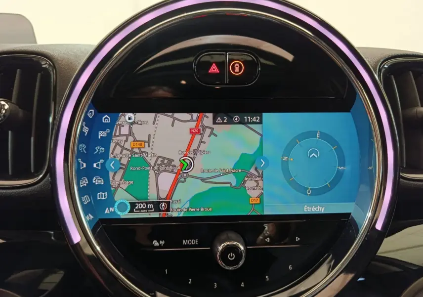 Écran tactile central rond du tableau de bord du MINI Countryman blanc, affichant la navigation GPS en mode jour.