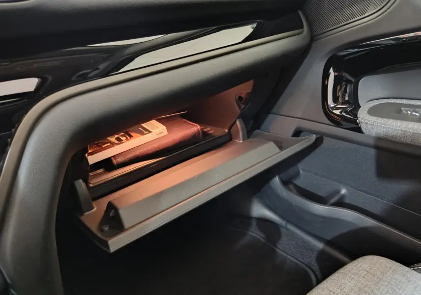 Vue intérieure côté passager du coffre à gants ouvert du MINI Countryman blanc, avec éclairage intérieur et détails en plastique noir.