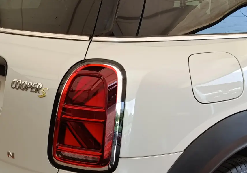 Gros plan sur le feu arrière gauche rouge d’un MINI Countryman blanc avec logo Cooper S visible.