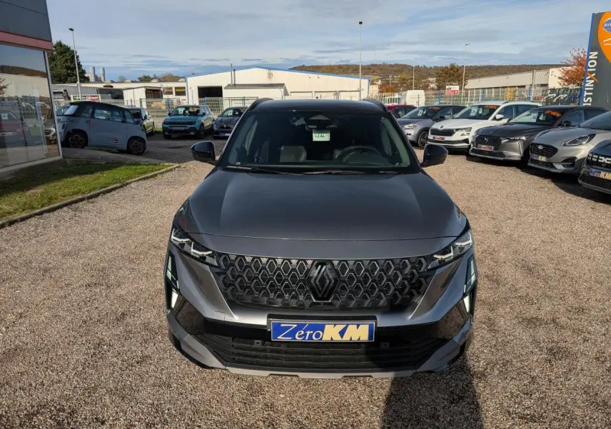 Vue avant d'un Renault Austral gris métallisé avec calandre noire et plaque Zéro KM visible en concession.