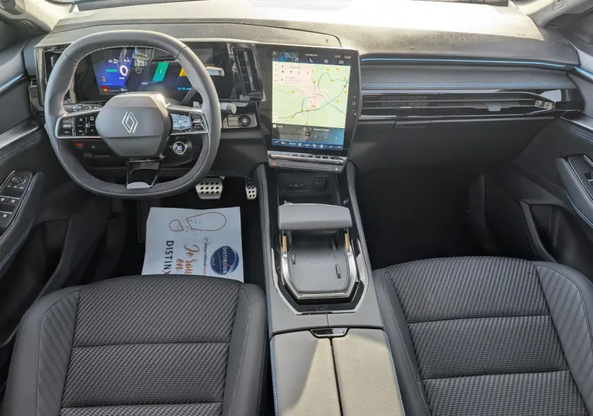 Vue intérieure avant du Renault Austral 2025 avec tableau de bord noir, écran tactile vertical et volant Alcantara.