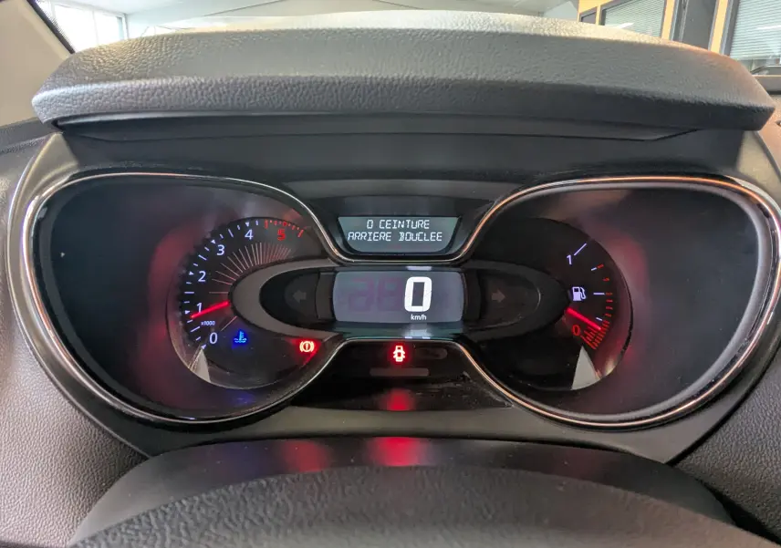 Vue rapprochée du tableau de bord numérique du Renault Captur gris clair, affichant la vitesse à 0 km/h et alertes allumées.