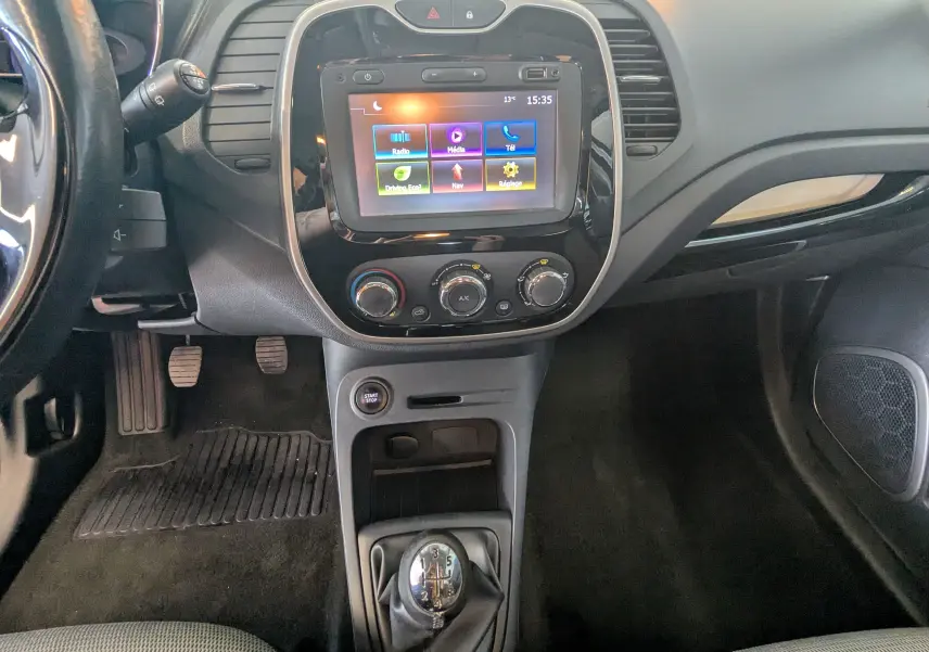 Vue intérieure centrée sur la console centrale d'un Renault Captur 2017, avec écran tactile et levier de vitesse manuel.