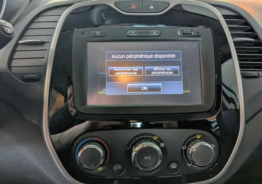 Vue rapprochée du tableau de bord gris noir du Renault Captur 1.5 dCi 90 Business avec écran tactile affichant un message d'absence de périphérique.