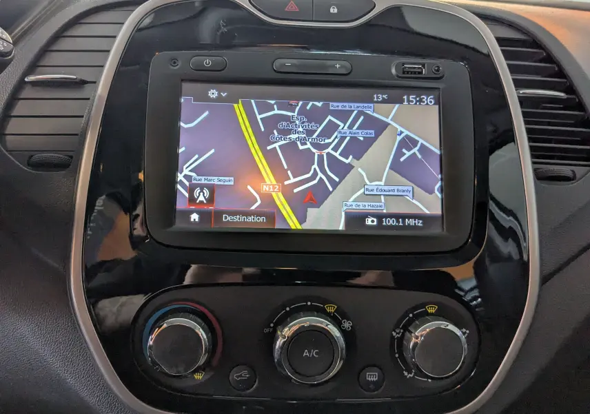 Vue rapprochée de l’écran GPS et des commandes de climatisation d’un Renault Captur gris clair de 2017.