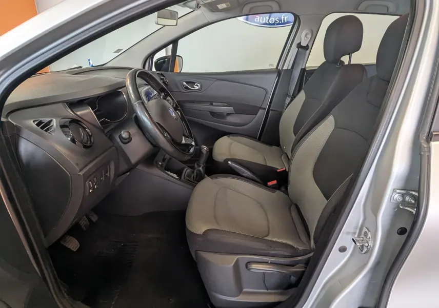 Vue intérieure côté conducteur du Renault Captur gris clair 2017, montrant les sièges bi-ton gris et noir et le volant.