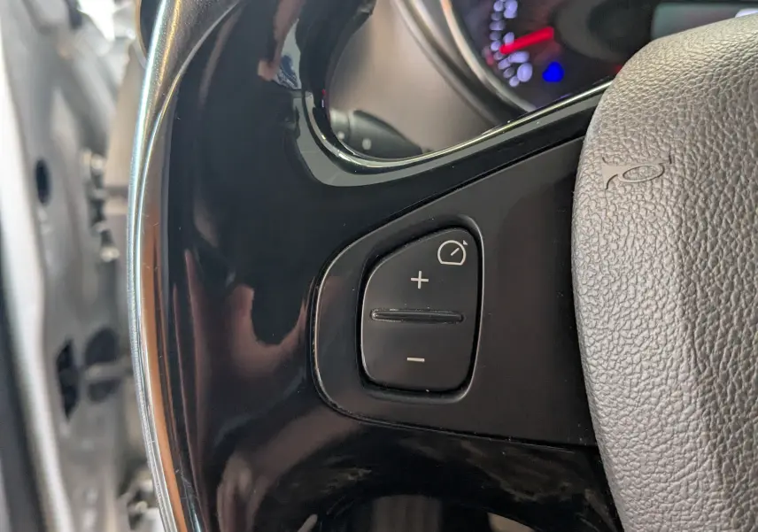 Gros plan sur les commandes de régulateur de vitesse au volant d’un Renault Captur gris clair, intérieur noir.