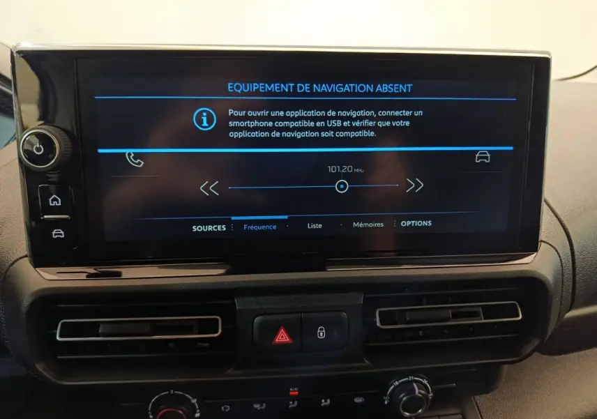 Vue rapprochée de l’écran central noir du tableau de bord du Peugeot Partner blanc, affichant un message d’équipement de navigation absent.