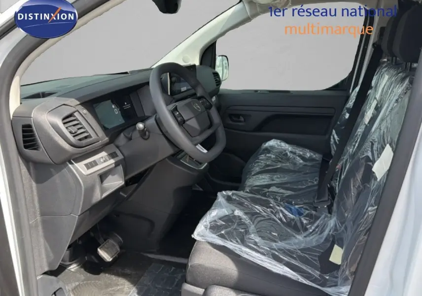 Vue intérieure côté conducteur du Citroën Jumpy blanc Kaolin, sièges avant protégés par film plastique.