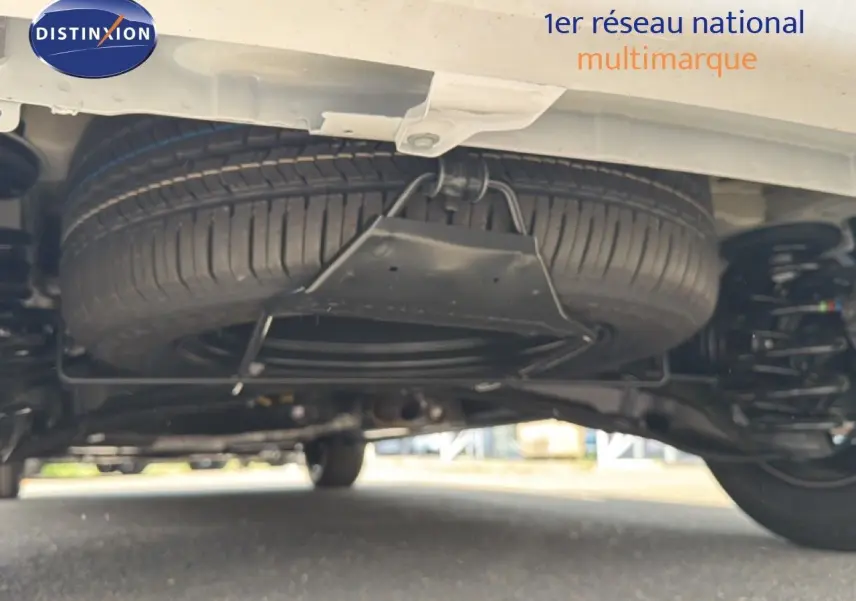 Vue en contre-plongée sous un Citroën Jumpy blanc Kaolin, mettant en valeur la roue de secours suspendue sous le véhicule.
