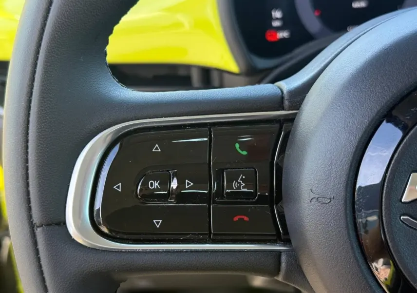 Gros plan sur les commandes multifonctions à gauche du volant d'une FIAT 500 électrique jaune Amalfi 2024.