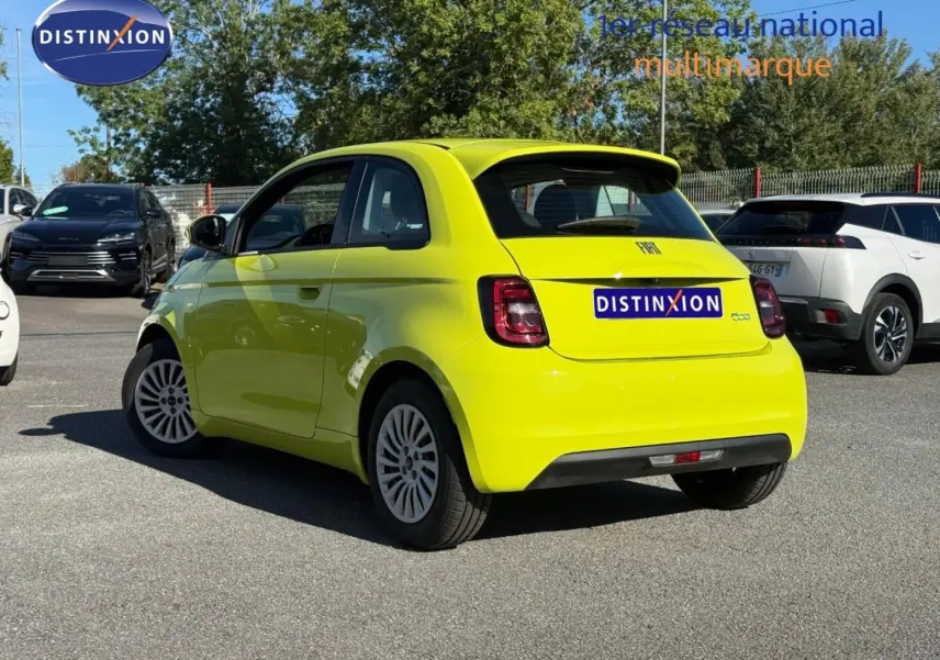 Vue 3/4 arrière droite d'une Fiat 500 électrique jaune Amalfi avec becquet et feux arrière LED, stationnée en extérieur.