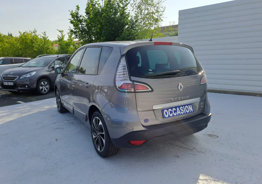 Renault Scénic III gris vue 3/4 arrière droit, avec feux arrière distinctifs et plaque "OCCASION" visible.