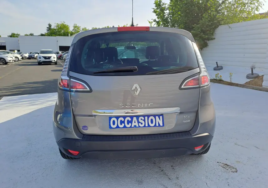 Vue arrière d'un Renault Scénic III gris 2016 avec plaque "OCCASION" sur un parking extérieur.