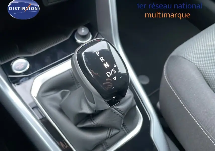 Gros plan sur le levier de vitesses automatique noir du Volkswagen T-Roc 1.5 TSI, intérieur tissu gris visible à droite.