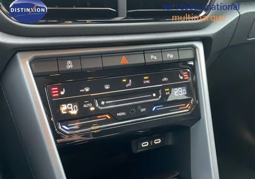 Vue intérieure centrée sur la console centrale du Volkswagen T-Roc noir, affichant la climatisation digitale à 29°C.