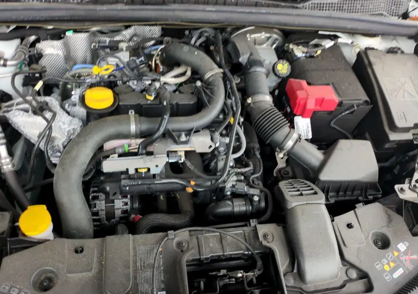 Moteur essence Renault Captur blanc 2024 vu de dessus, avec plusieurs bouchons jaunes et batterie à capuchon rouge.