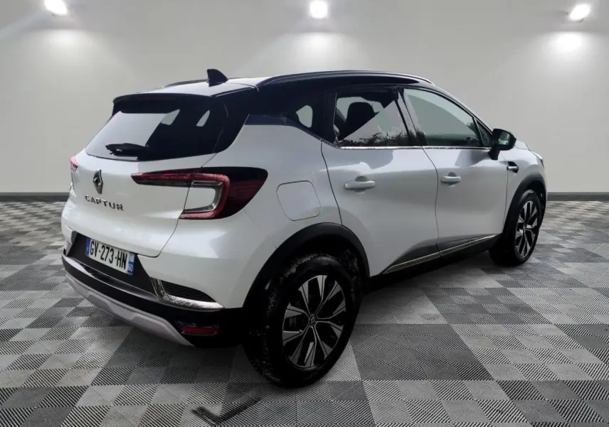 Vue 3/4 arrière droite d’un Renault Captur blanc 2024 avec toit noir et jantes alliage bicolores.