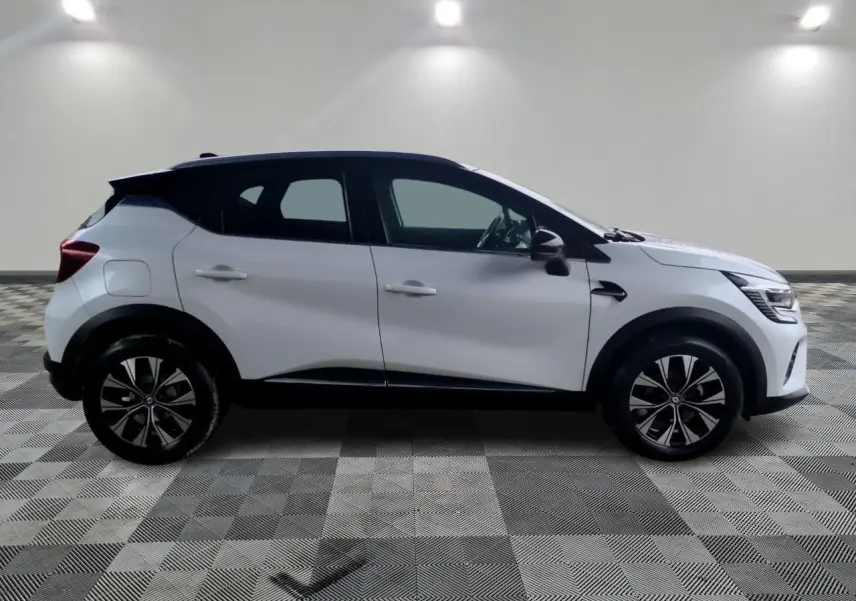 Profil côté gauche d'un Renault Captur blanc 2024 avec toit noir et jantes alliage bicolores dans un studio.